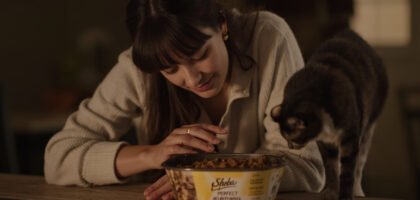 Young woman offering Sheba Perfect Portions Wet Cat Food to an elegant feline