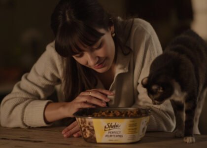 Young woman offering Sheba Perfect Portions Wet Cat Food to an elegant feline